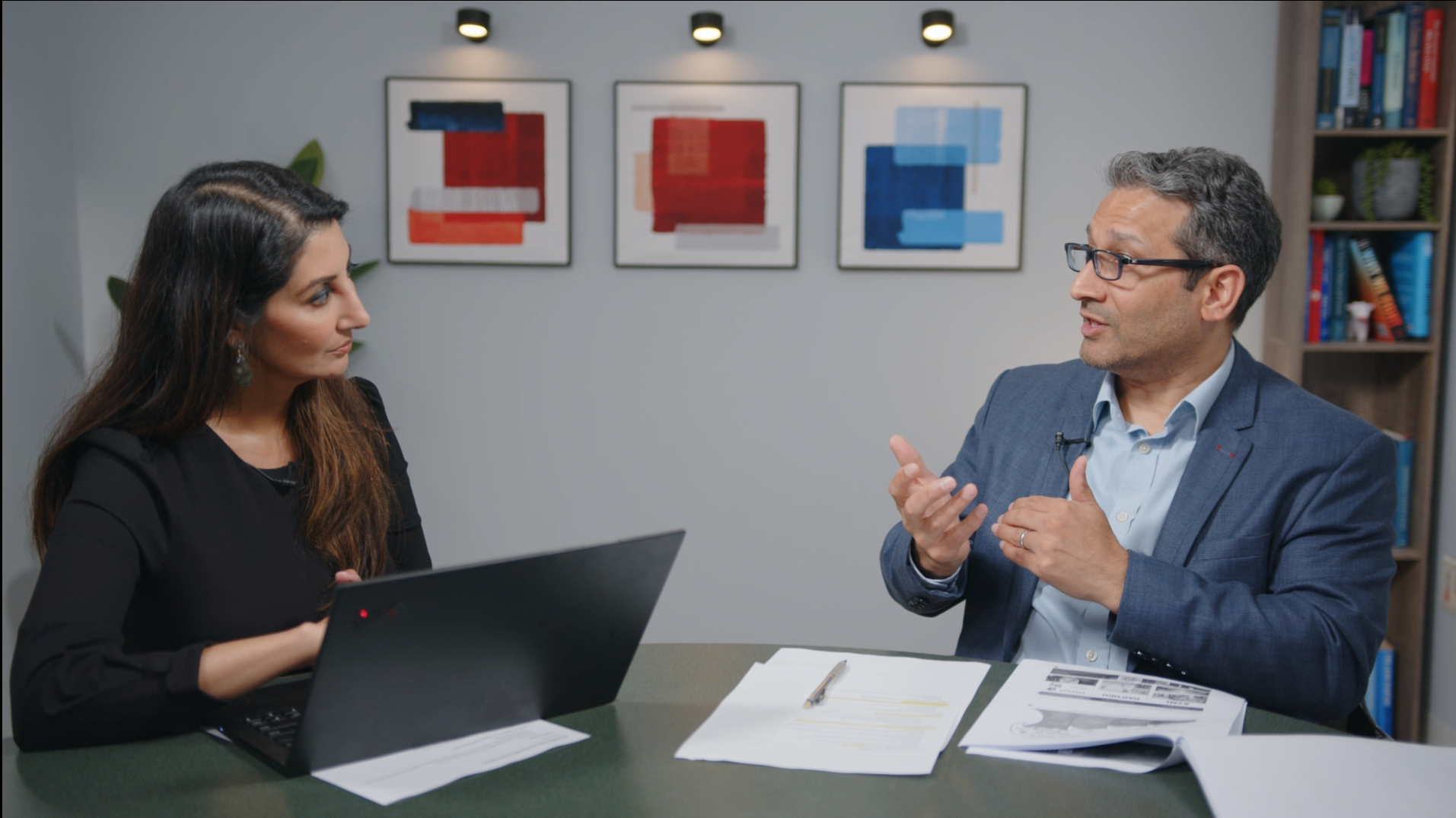 Uday Cheruvu and Apurva Schwartz sit at a table in an office.